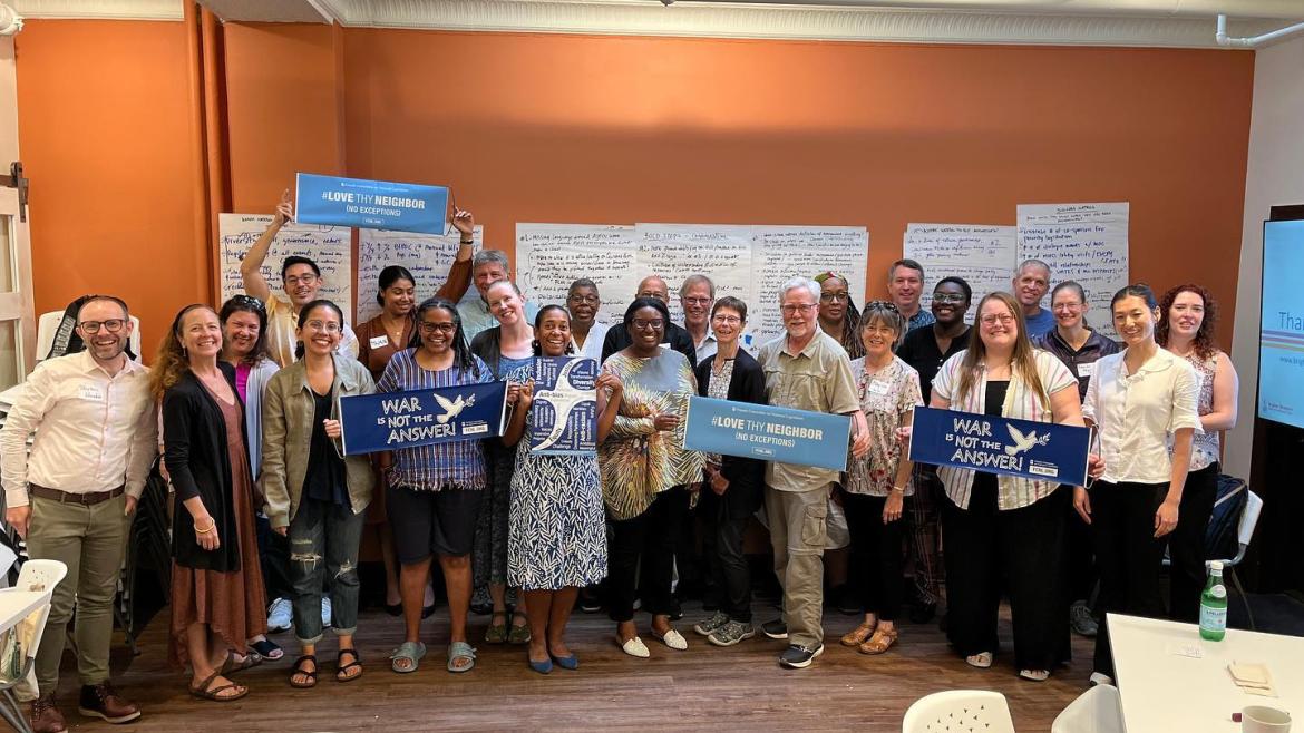 A group of staff and board members gathered in the meeting room, posing with advocacy signs.