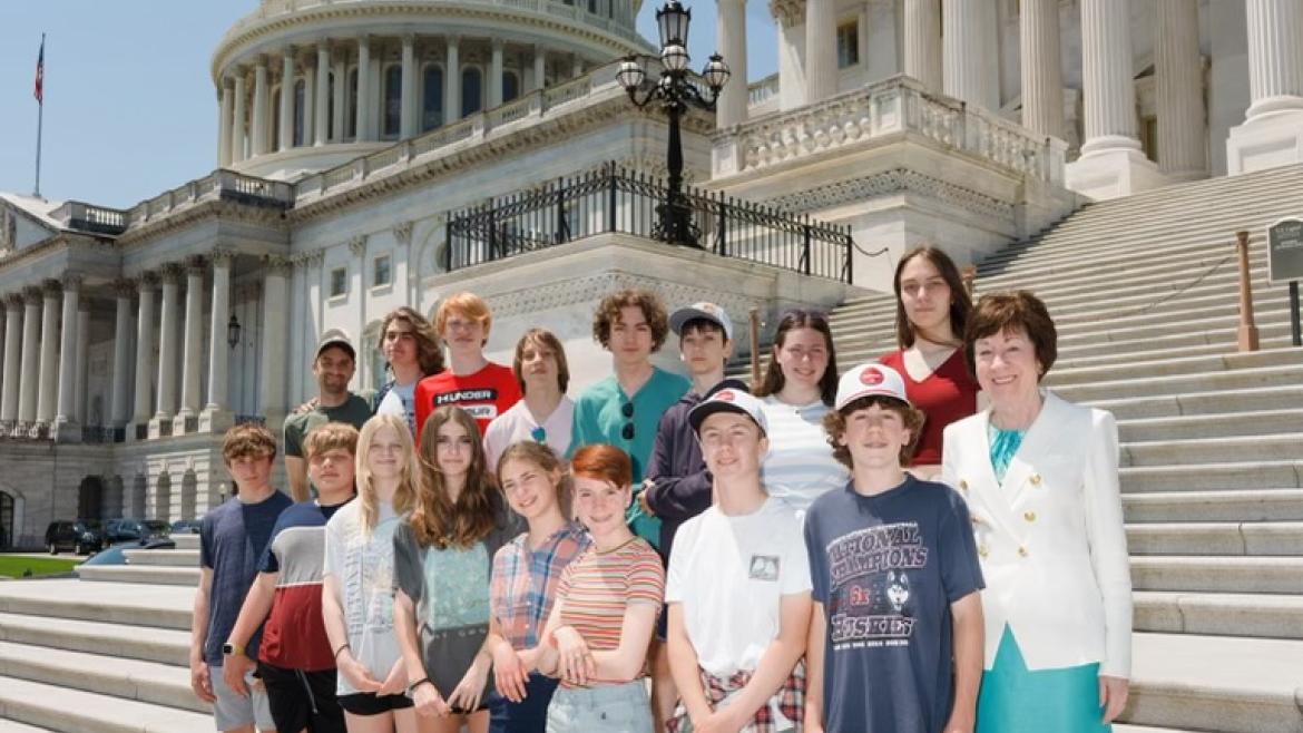 Group poses with Senator Collins outside of the Capitol building